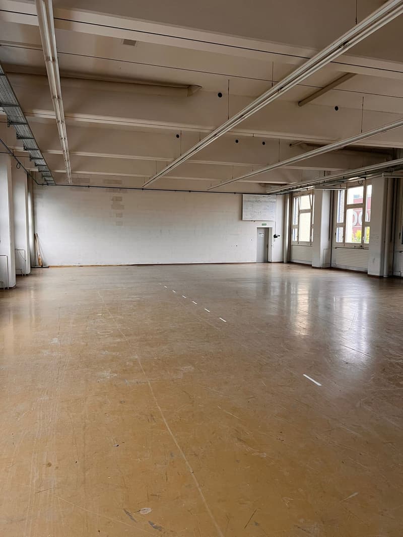 Empty room, wooden floor, high ceiling, metal beams, white walls, windows, doors