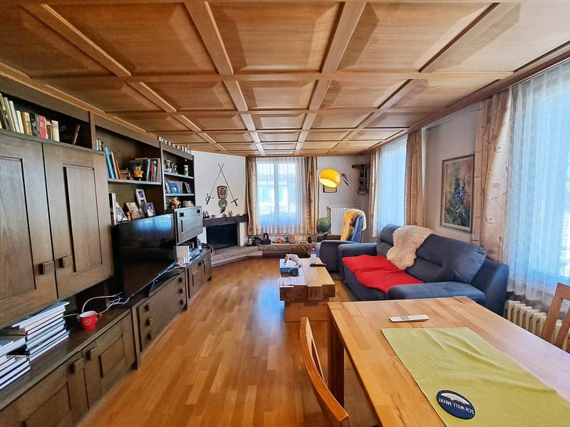 Spacious living room with wooden coffered ceiling, built-in bookshelves, sofa, coffee table, and a fireplace
