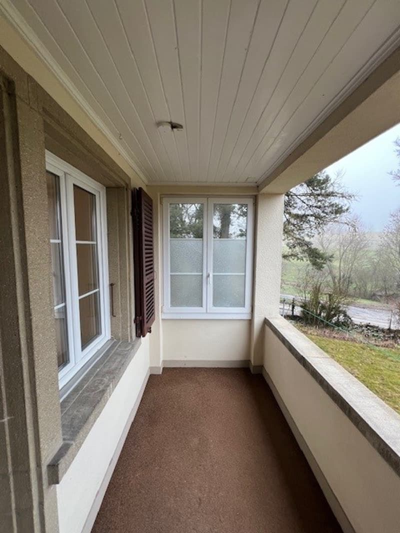 empty room with balcony, windows, white ceiling, brown floor, white walls