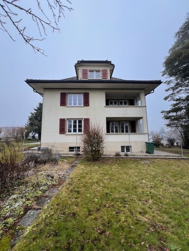 2 story house, white painted, red shutters, balcony, grass lawn, green trash bin