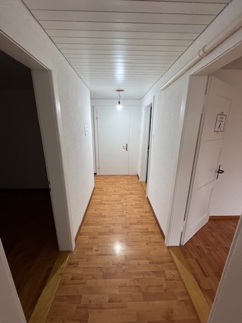 Empty hallway with wooden flooring and white walls