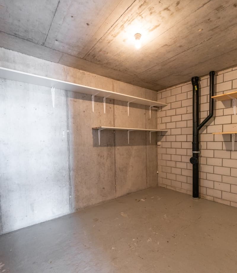 empty room, concrete walls, white shelves, brick wall, black pipe
