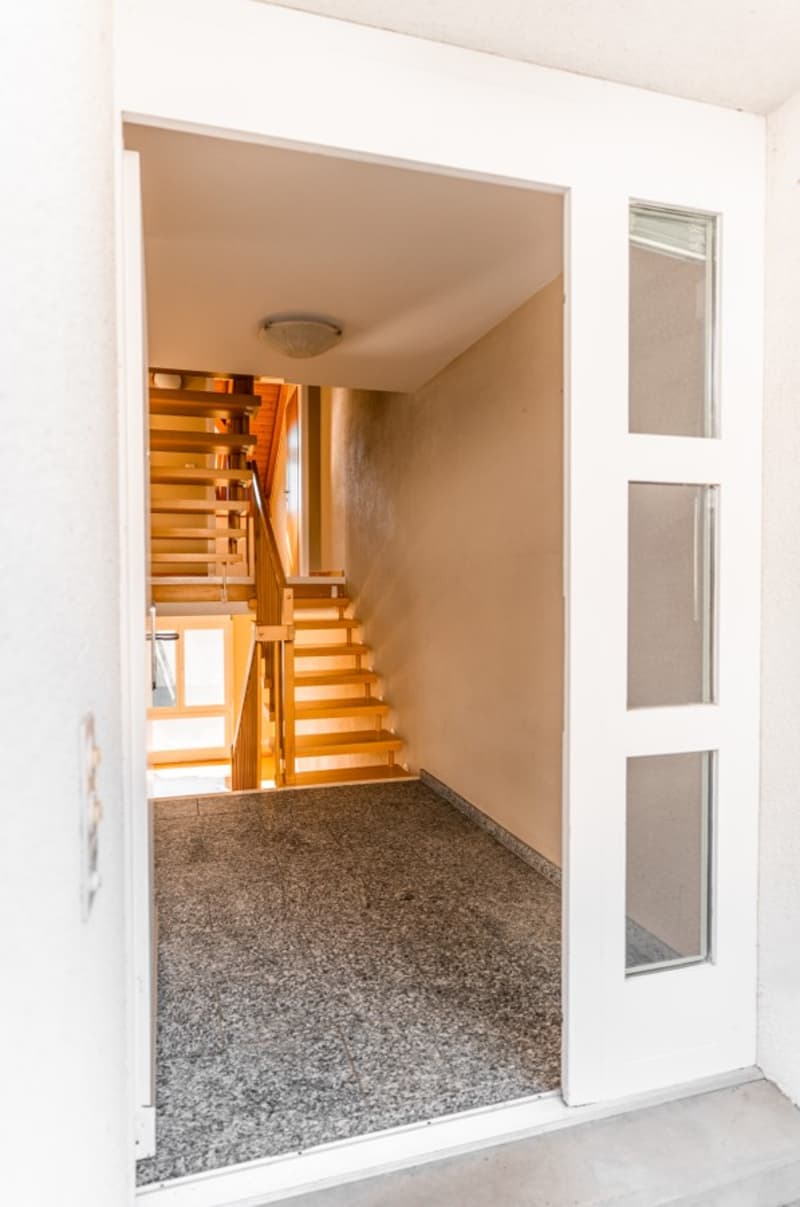 Open door, wooden staircase, tiled floor, white walls, glass door