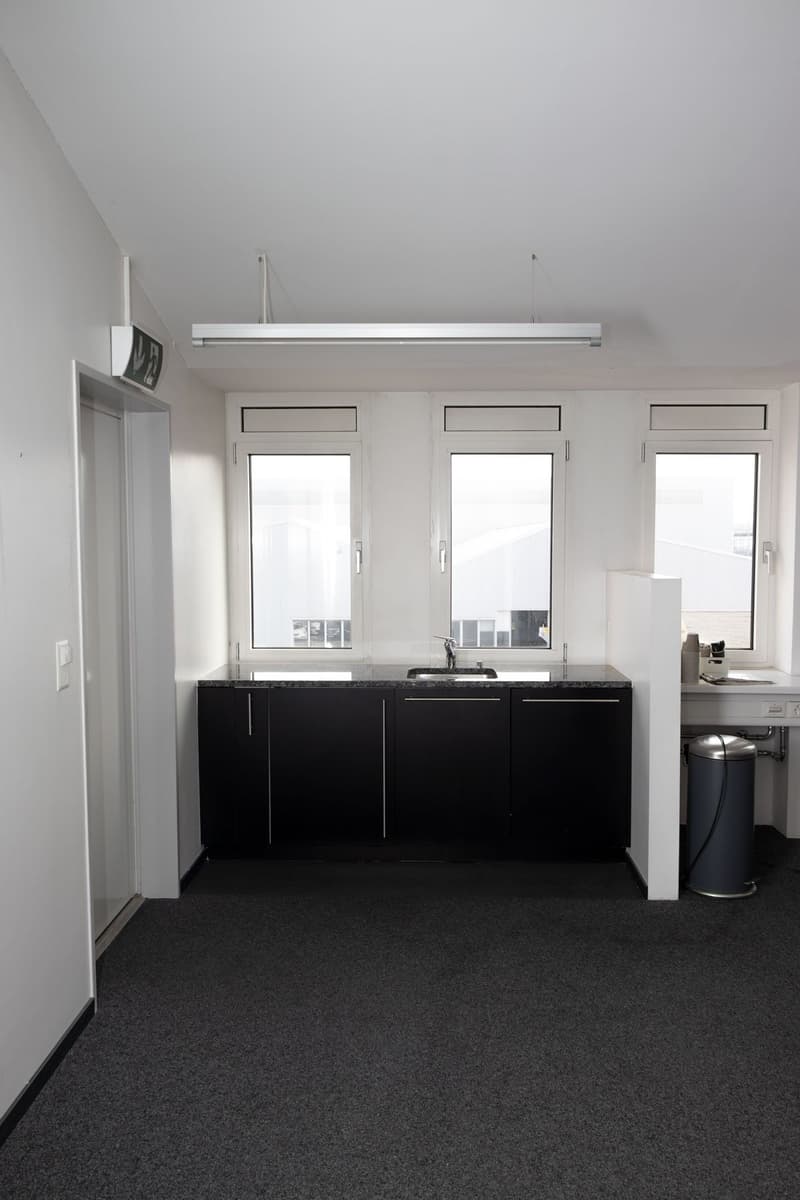 empty room, black cabinets, granite countertop, sink, windows, trash bin