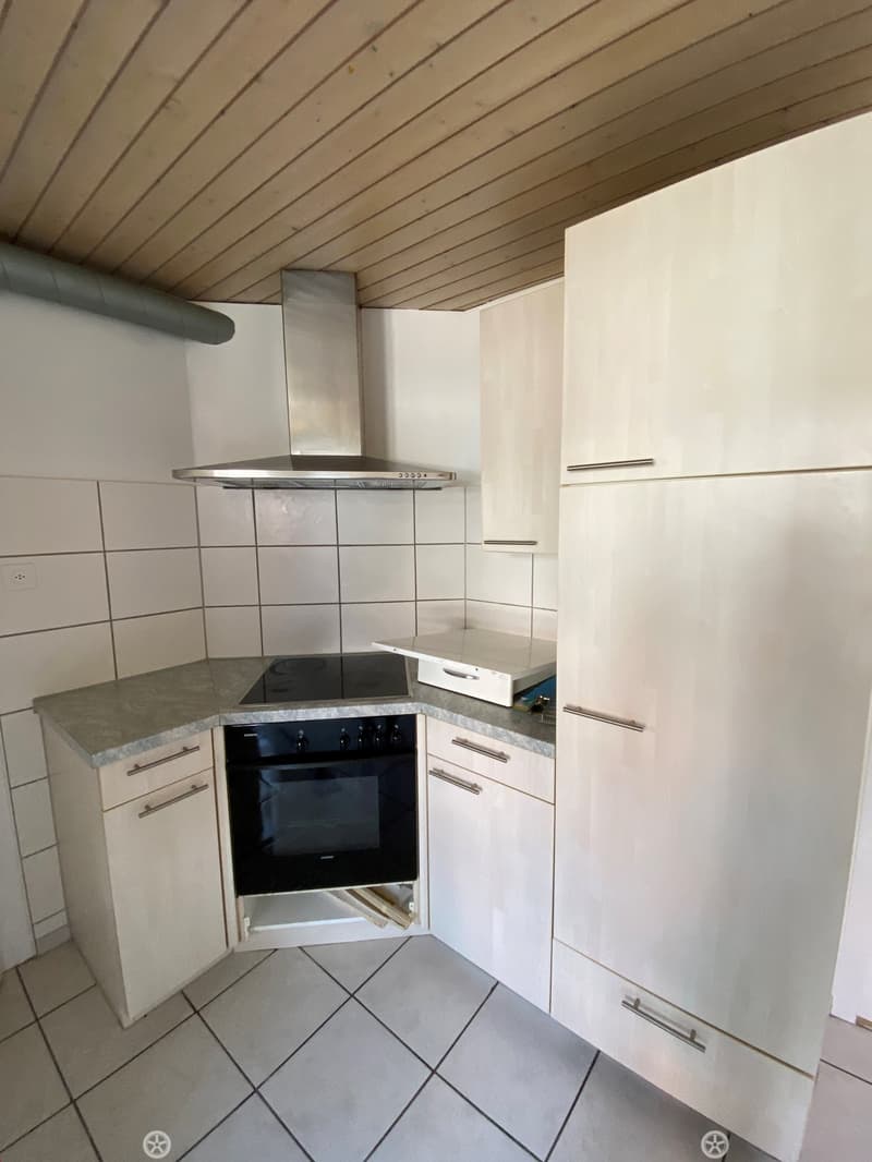 modern kitchen with white cabinets, tiled floor, black oven, stainless steel hood, granite countertop