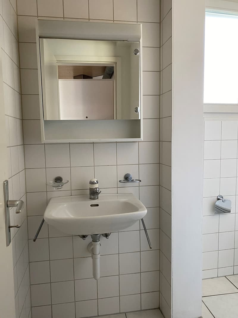 Bathroom with white tiles, a sink, a mirror, and a window