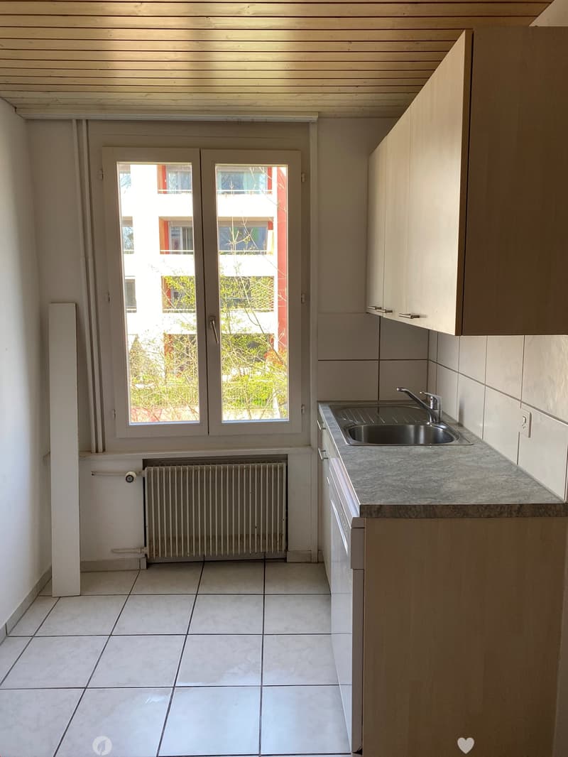 Empty kitchen with white tiles, wooden ceiling, white walls, a sink, a faucet, a window, and a radiator
