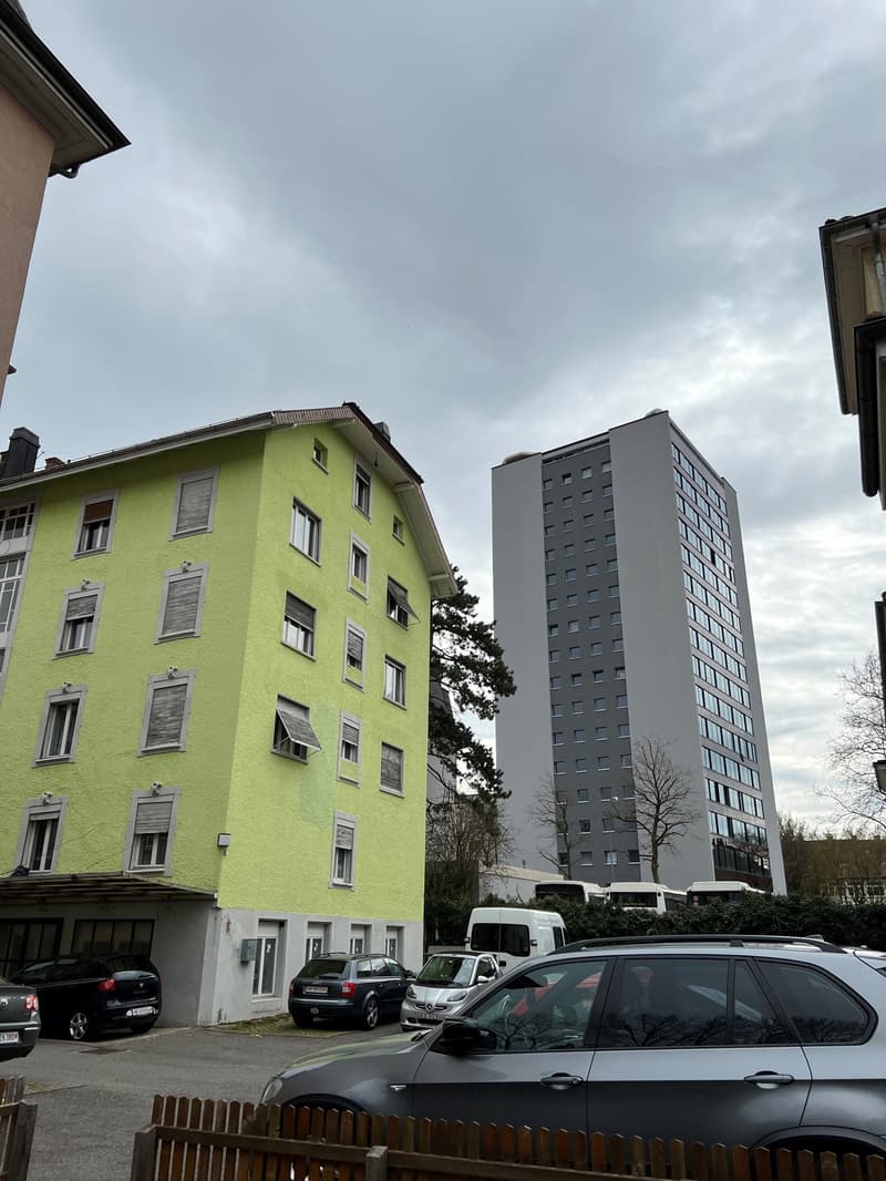 Two buildings, one is a tall building with many windows, the other is a smaller building with yellow walls and multiple windows