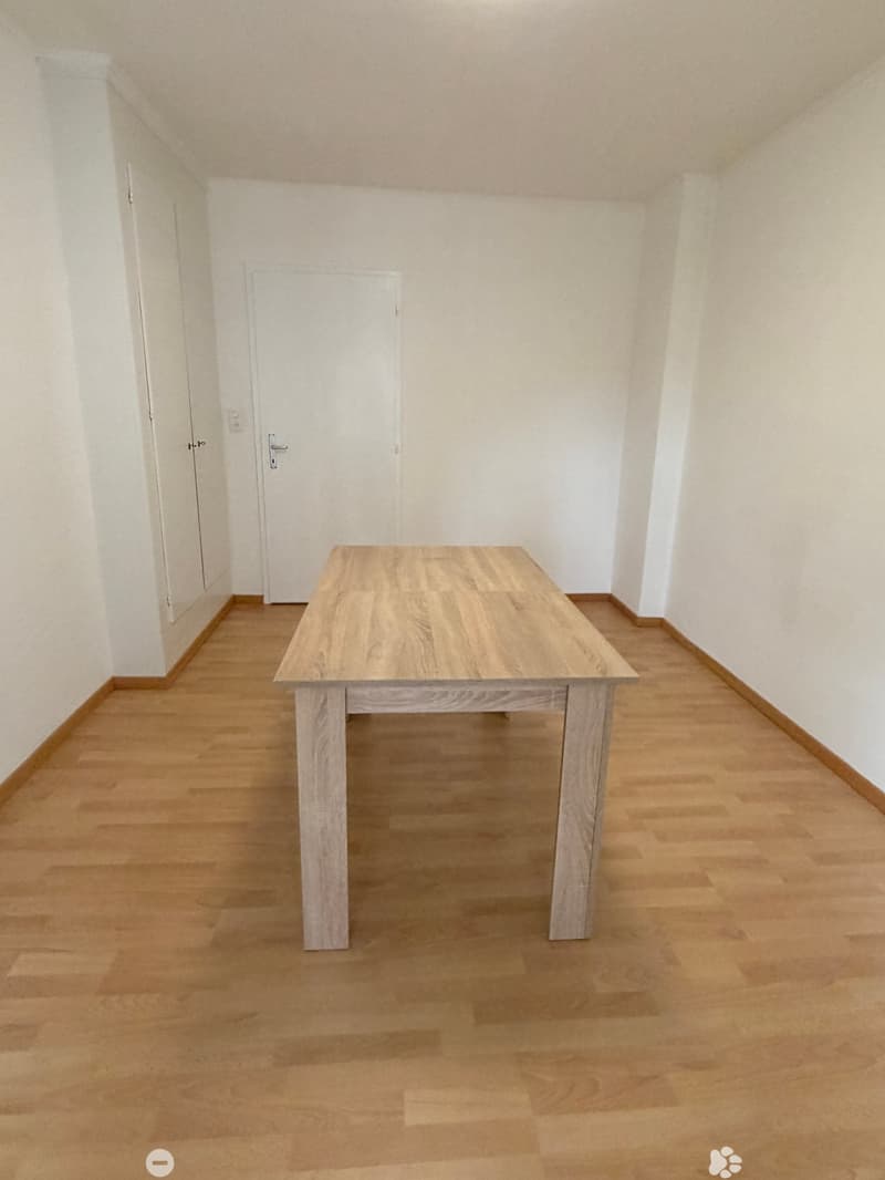 empty room, wooden floor, white walls, large wooden table, two doors