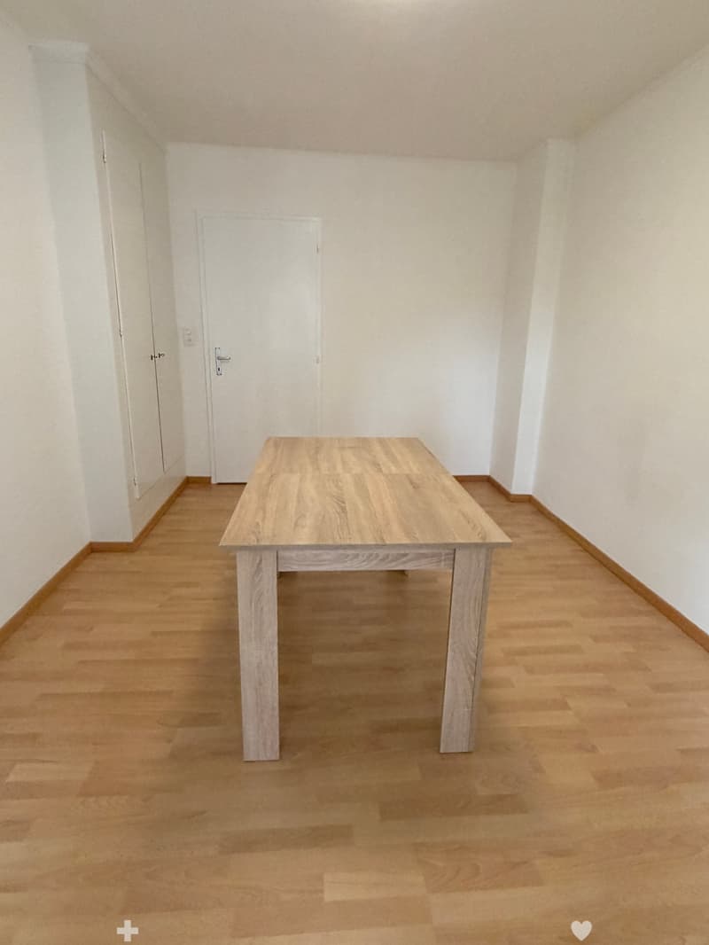 empty room, wooden floor, white walls, large wooden table, two doors