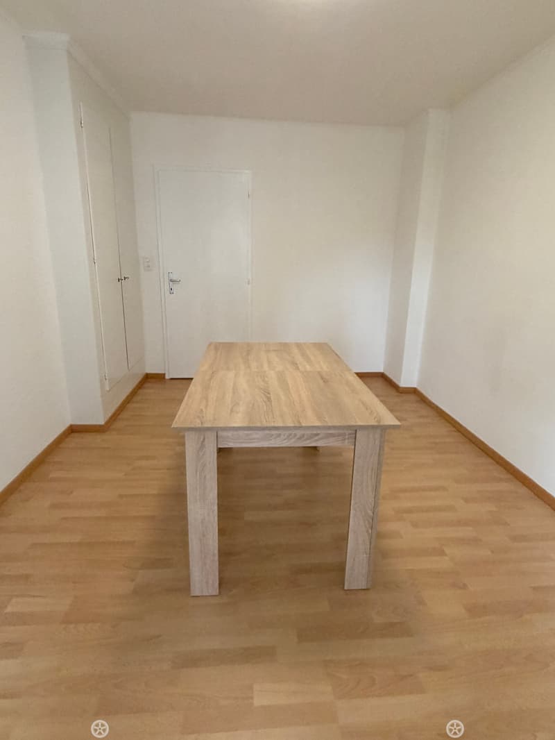 empty room, wooden floor, white walls, large wooden table, two doors