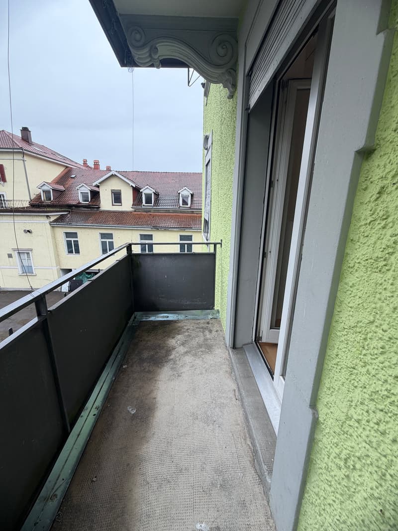 Balcony with metal railing, green wall, open door