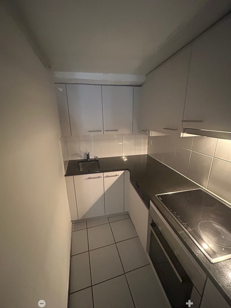 kitchen with white cabinets, black countertop, silver sink, induction stove, built-in oven, and tiled floor