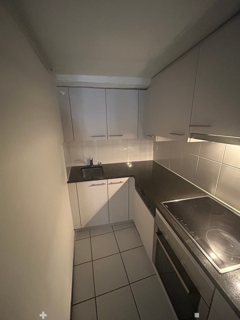 kitchen with white cabinets, black countertop, silver sink, induction stove, built-in oven, and tiled floor
