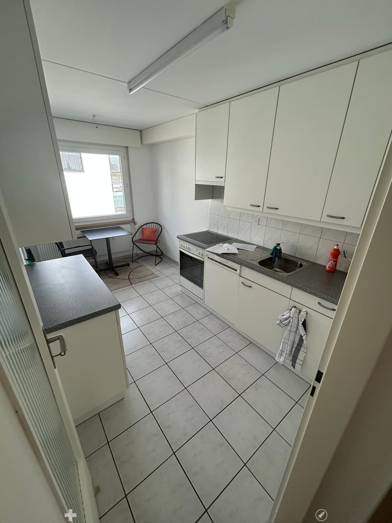 modern kitchen with white cabinets, tiled floor, white countertops, sink, oven, window, chairs, table
