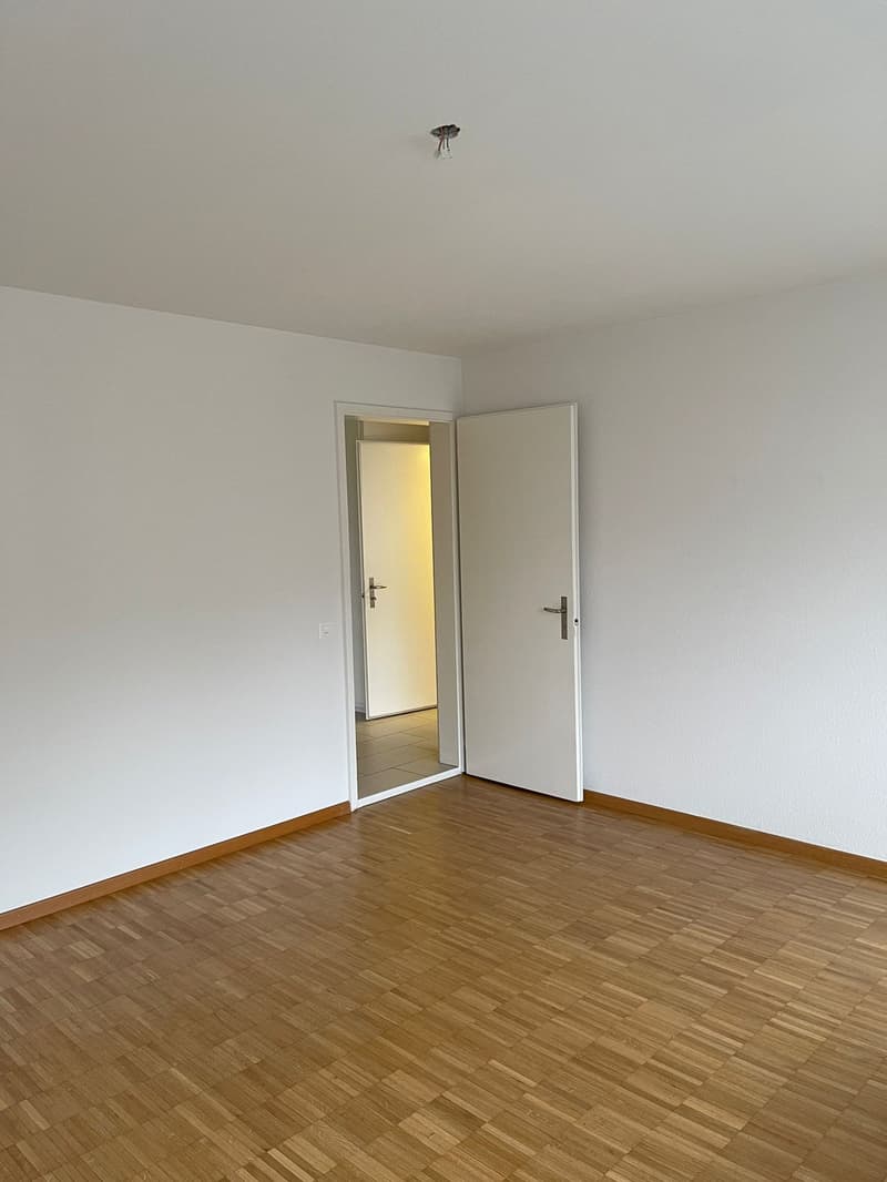 empty room, white walls, wooden floors, white door, open door leading to another room