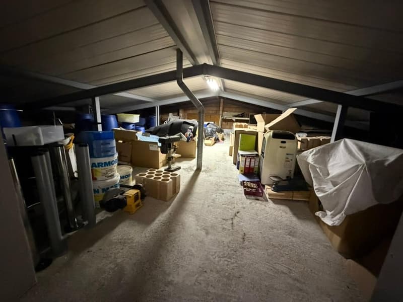 large room, filled with various items, boxes, barrels, equipment, wooden pallet, and covered items