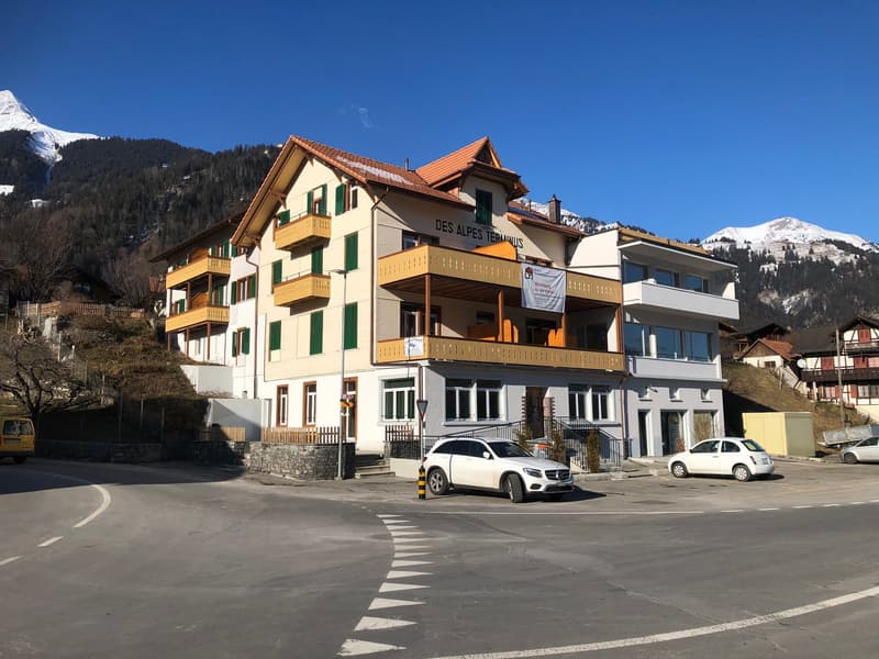 3 story building, yellow balconies, white walls, red roof, mountain view