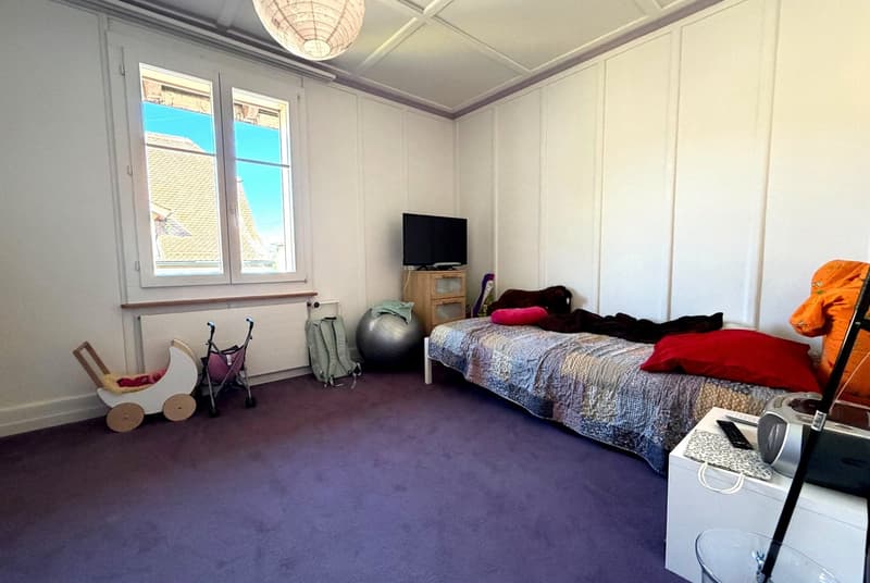 bedroom with bed, TV, exercise ball, stroller, backpack, lamp, radiator, window