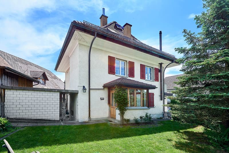 two-story house with a basement, white exterior walls, red shutters, red roof tiles, wooden door, small garden