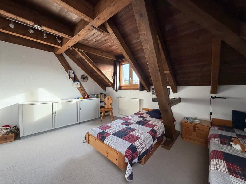 bedroom with two beds, wooden ceiling, wooden floor, wooden nightstands, radiator, wardrobe, window, toys, chair, books