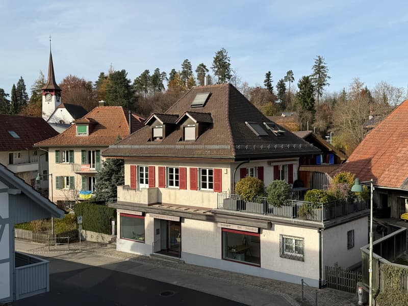 a 3 story house with brown roof, red shutters, and a terrace on the top floor