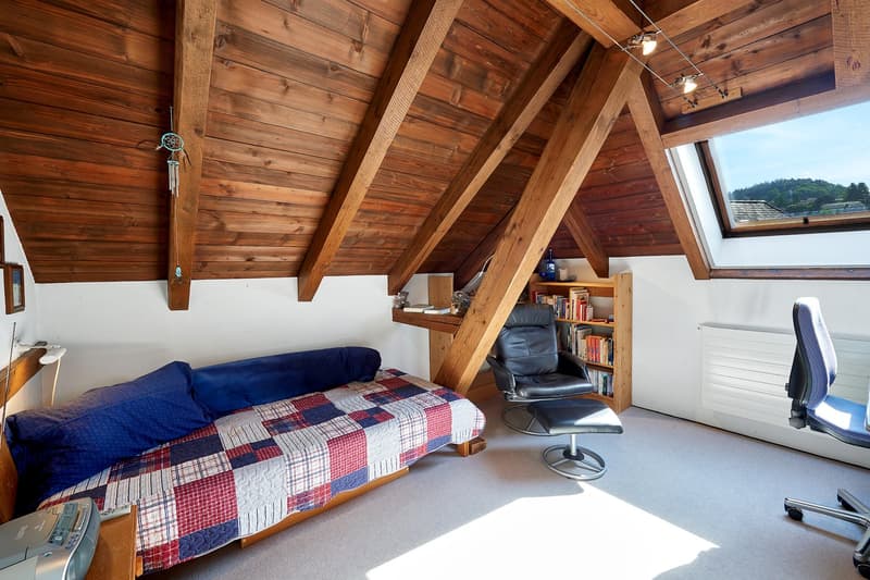 attic room, wooden beams, books, chair, bed, desk, and rug