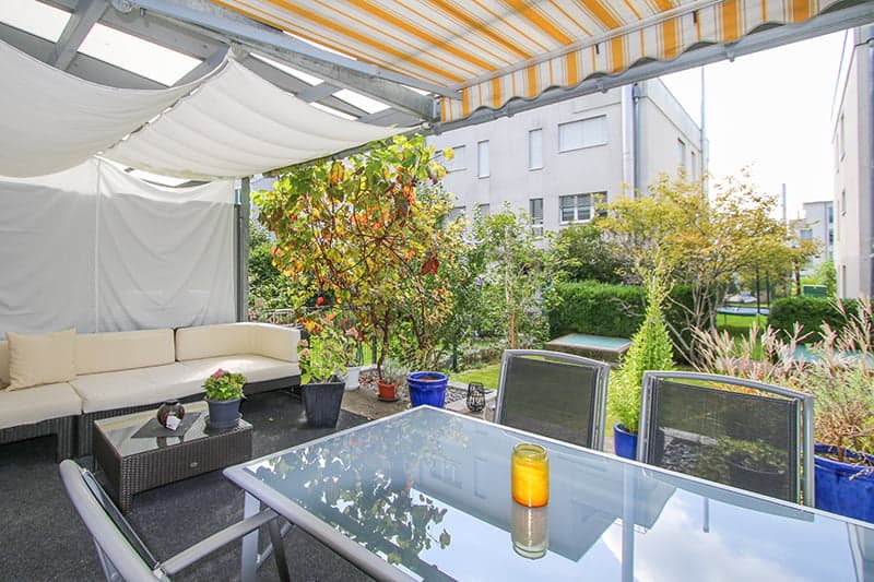 white sofa, tables, chairs, canopy, plants, and candles