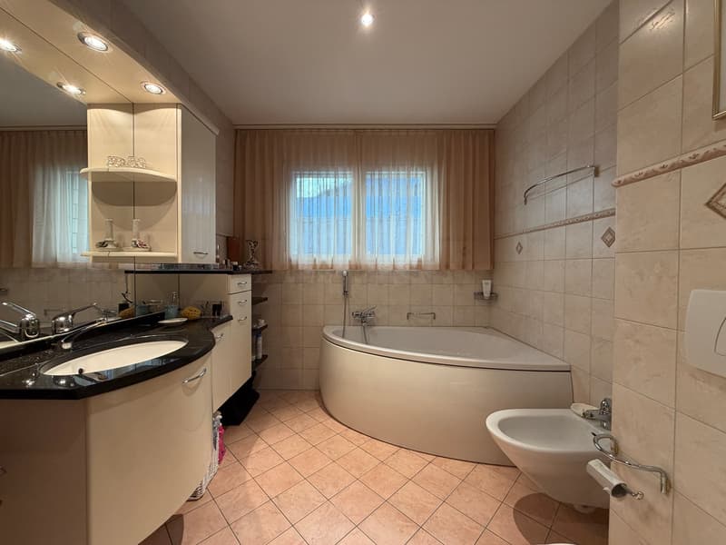 White bathtub, black countertop, white cabinets, white sink, tile flooring, curtain, wall mounted soap holder, and towel hanger