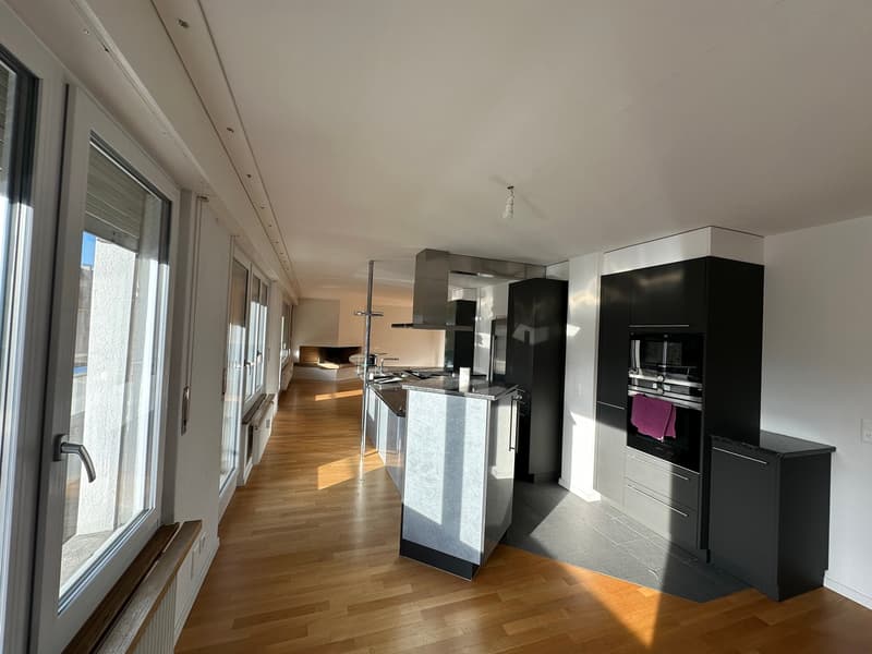 modern kitchen with island, black cabinets, stainless steel appliances, wooden floor, fireplace, large windows