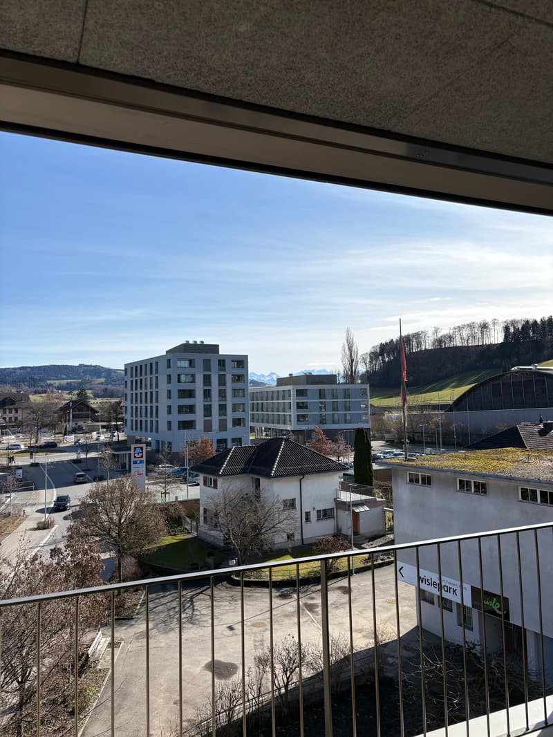 Balcony with railing, city view, apartment buildings, road, mountains in the distance