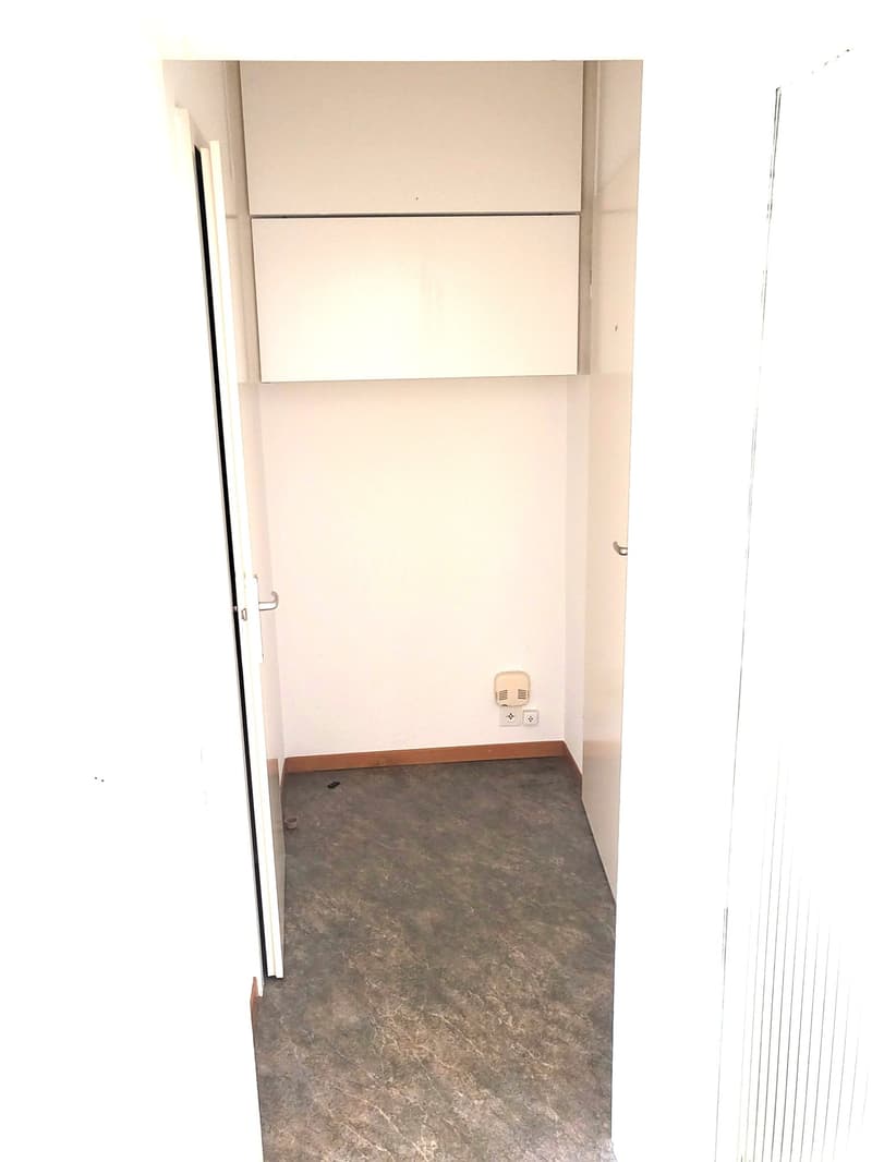 Empty room with two doors, white cabinets mounted on the wall, power outlets, wooden baseboard.