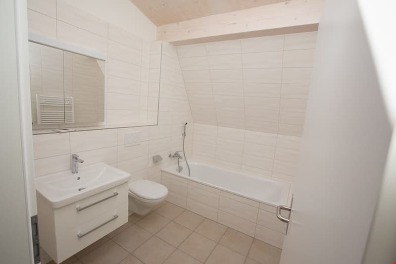 white tiles, bathtub, toilet, sink, mirror, light wooden ceiling