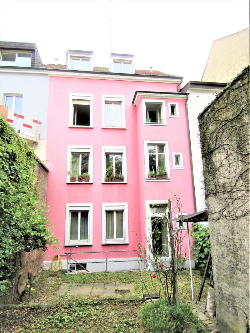 pink, multistory house, multiple windows with white trim, plants on window sills