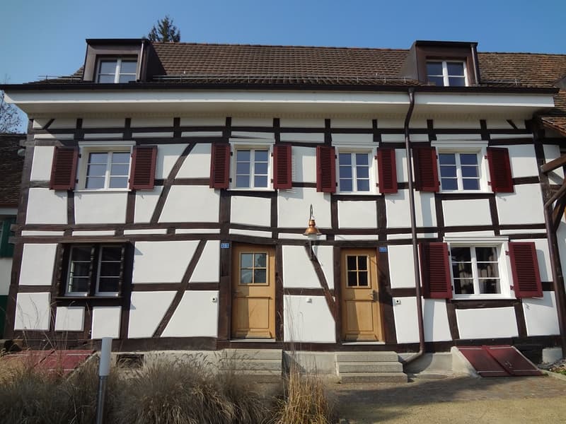 Two story house, white walls, brown trim, red shutters, two doors