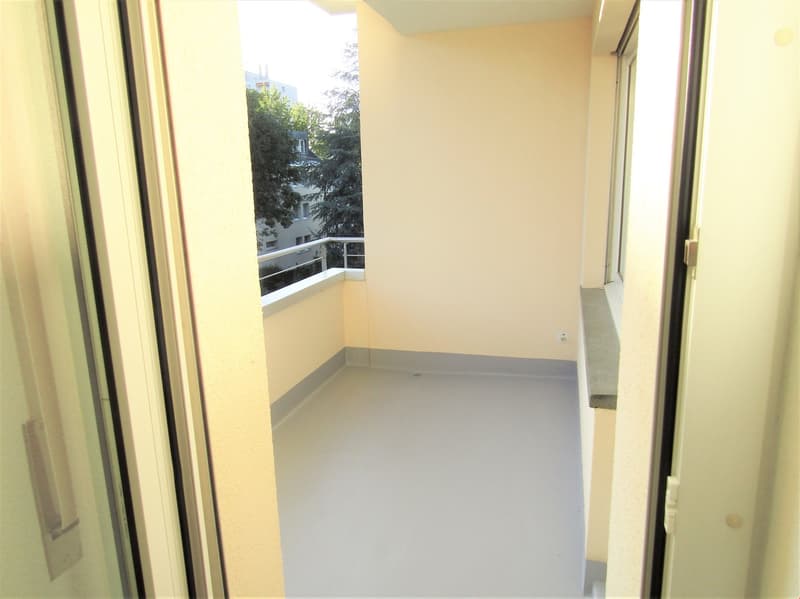 Empty balcony with railings, white walls, gray floor, power outlet