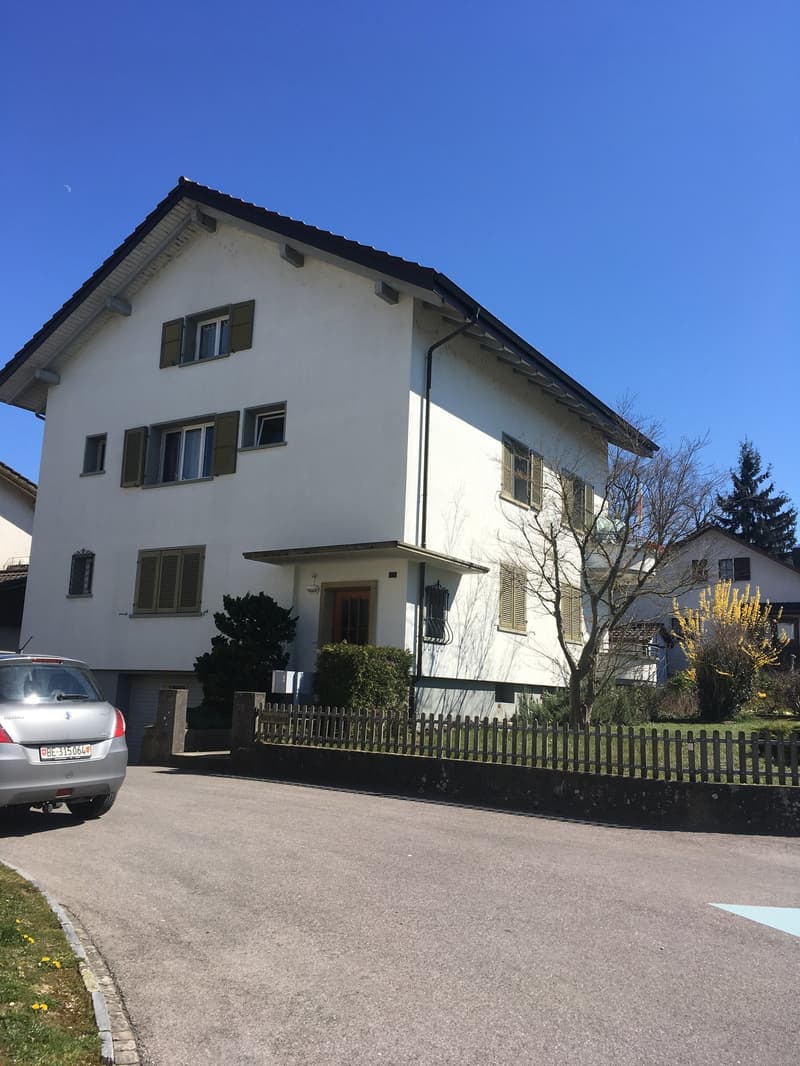 3 story house, white exterior, brown roof, multiple windows, small garden, driveway