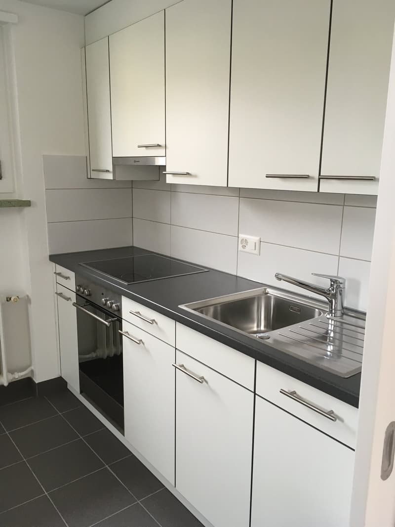 modern kitchen with white cabinets, black countertops, stainless steel sink, electric stove, oven, dishwasher, and washing machine