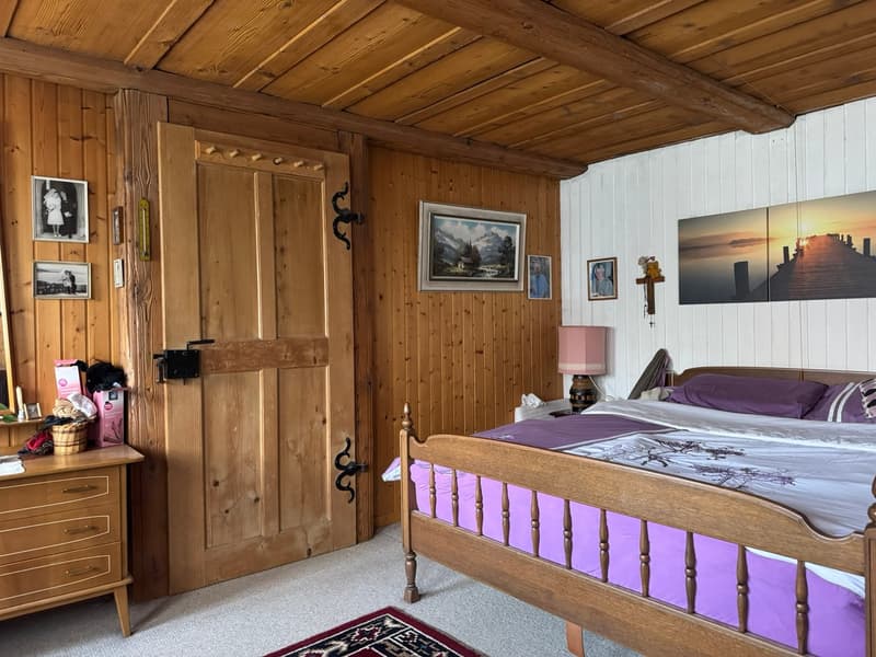 wooden walls, wooden bed, wooden dresser, carpet, framed pictures, lamp, basket, pillows