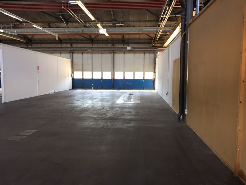 Large open warehouse space with concrete floor, white walls, and overhead lighting. The space appears to be empty and ready for use.