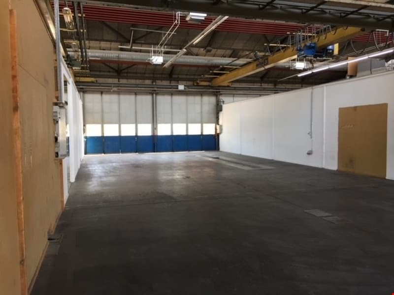 Large open warehouse space with concrete floor, high ceiling, and overhead cranes or equipment visible.