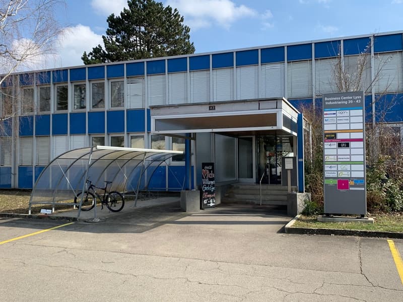 2-story commercial building with blue and gray exterior, covered entrance, and a bicycle rack outside