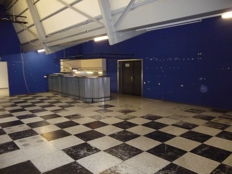Large open kitchen area with a black and white checkered tile floor, a long counter with a built-in dishwasher, and blue walls with a starry night sky mural.