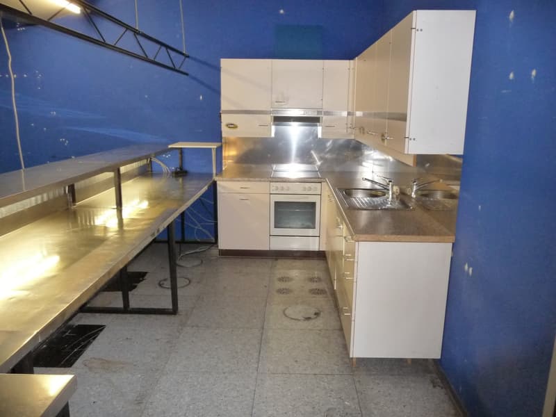 Stainless steel appliances, including a dishwasher, granite countertops, white cabinets, and a tiled floor.