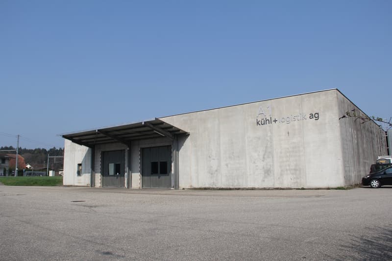 Industrial building, concrete walls, double doors, flat roof, large front area, empty parking lot