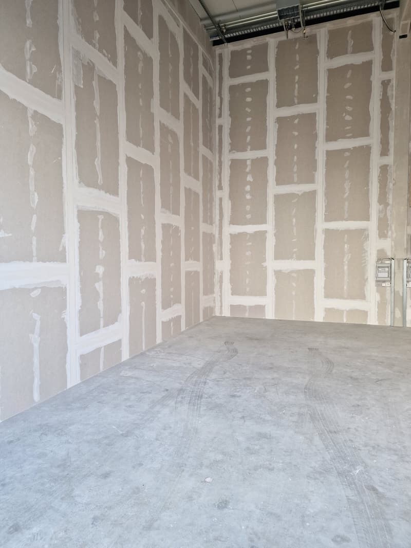 large empty room with unfinished walls, clean concrete floor, white paint on walls