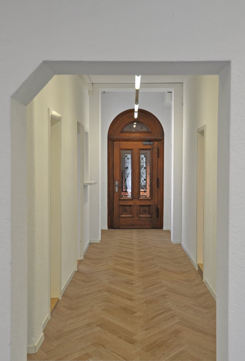 wooden floor, white walls, arched wooden door, hallway