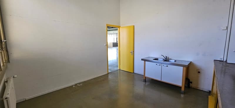 Empty room with white walls, concrete floor, yellow door, sink, radiator