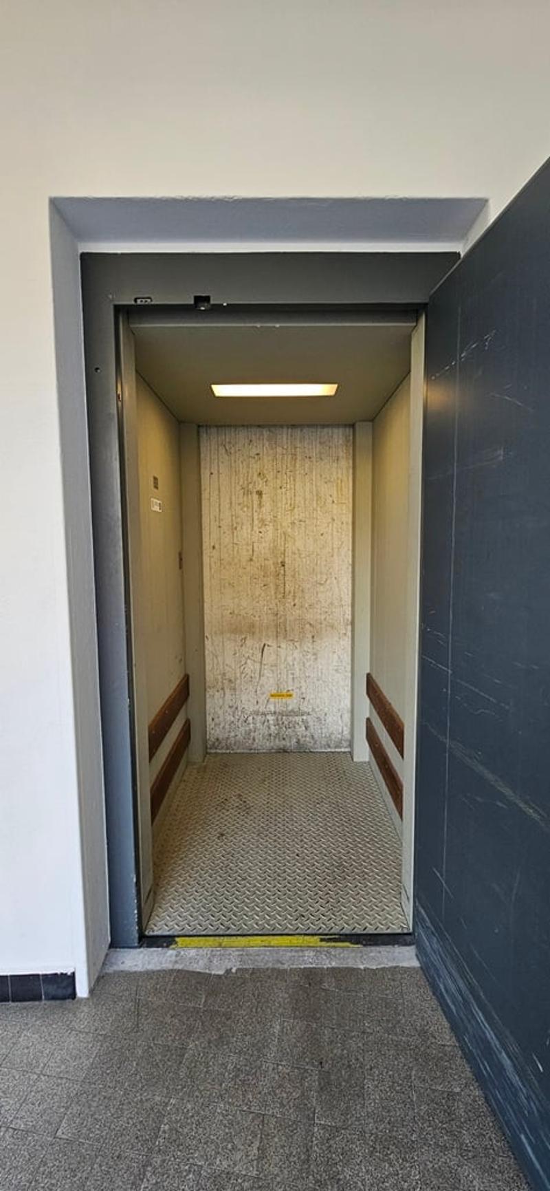 elevator with wooden interior, metal floor, open door