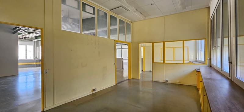 Empty room with yellow walls, glass windows, concrete floor, and a wooden counter